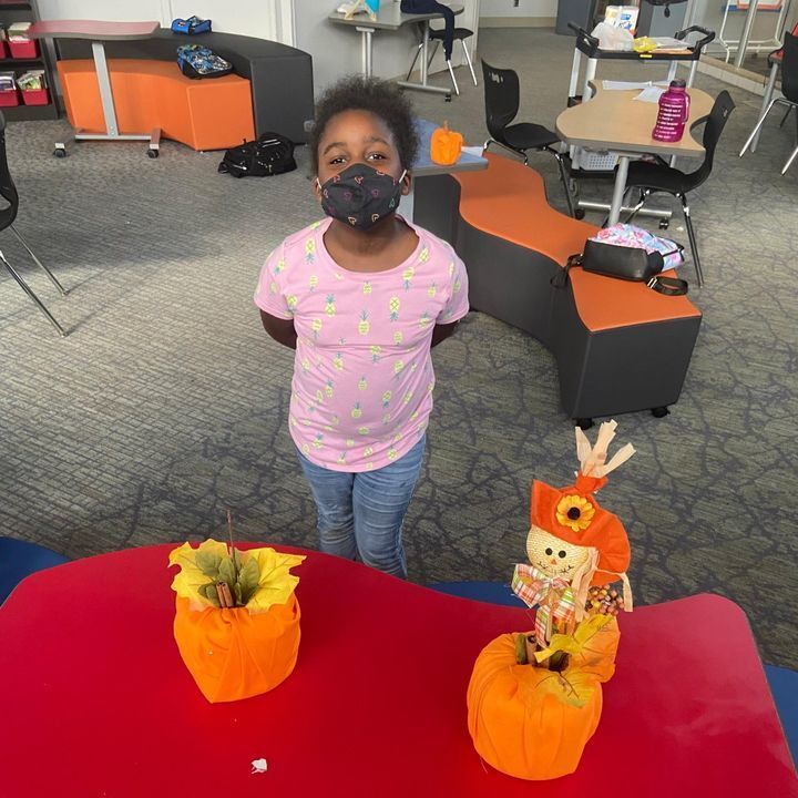 Student Madison E. stands with her paper pumpkins