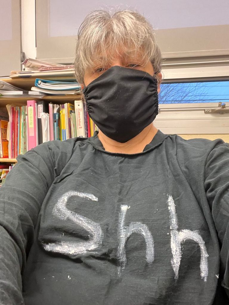 Teacher wearing a shirt reading "shh"