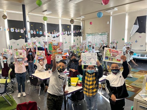 Students hold up art projects